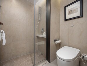 Un baño moderno con ducha de vidrio, un inodoro y un cuadro en la pared.