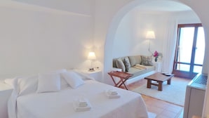 A hotel room with a bed, a small table, a sofa, and a desk. - My Rental Homes - Villa Zenas with stunning pool overlooking the Aegean sea. (Mykonos)