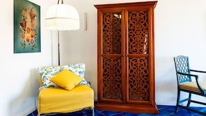 Een kamer met een bed, een houten kast, een stoel en een vloerlamp.