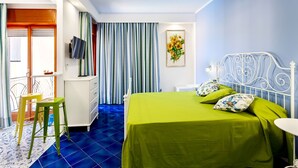 Een kamer met een bed, een televisie, een stoel en een raam met gordijnen.
