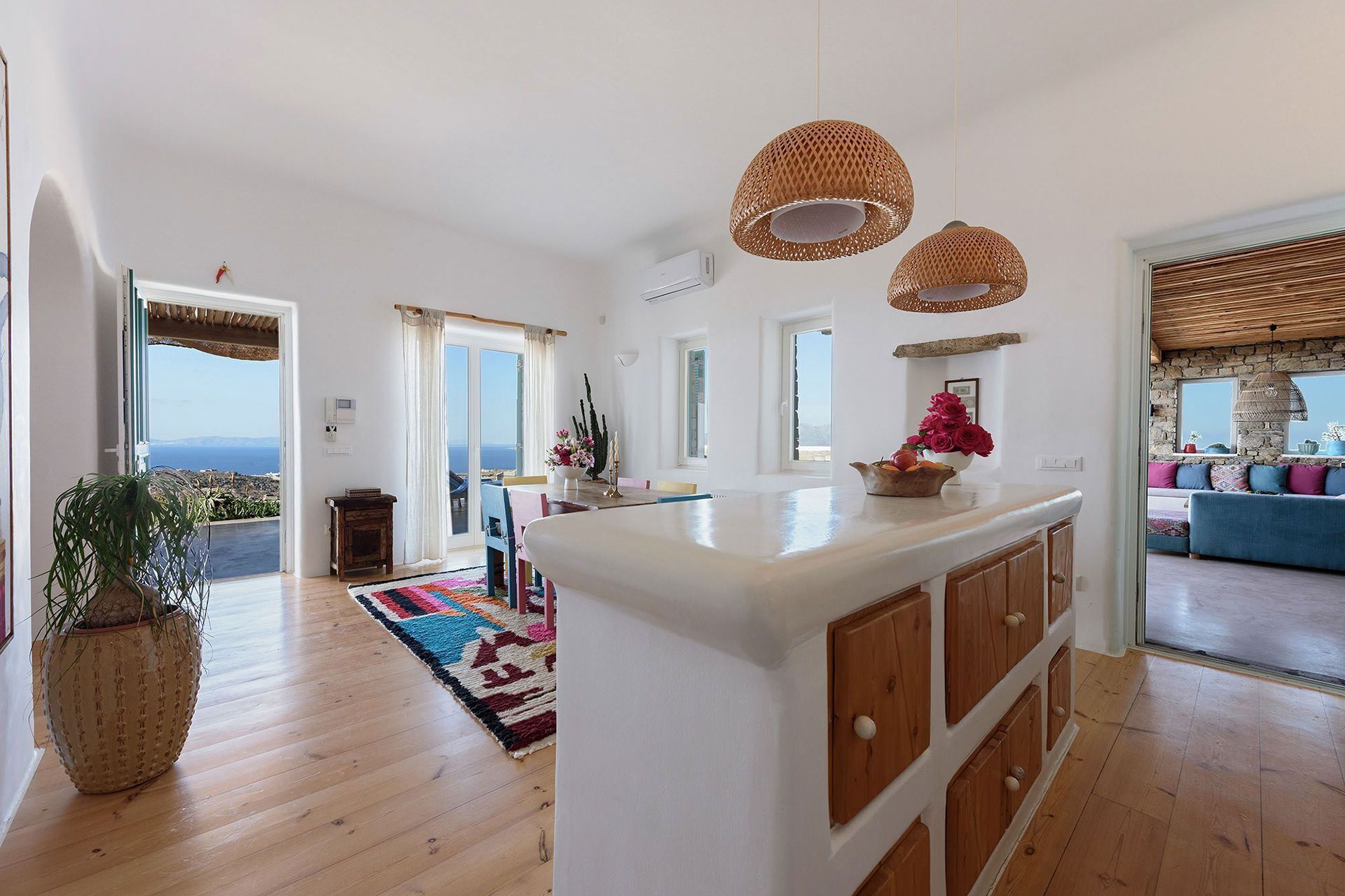 A spacious living area with a large island, wooden flooring, and a view of the sea.