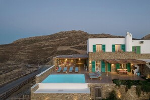 Uma villa moderna com piscina, área de estar externa e vista para a paisagem ao redor.