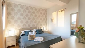 A bedroom with a bed, bedside tables, a nightstand, a mirror, and a window.