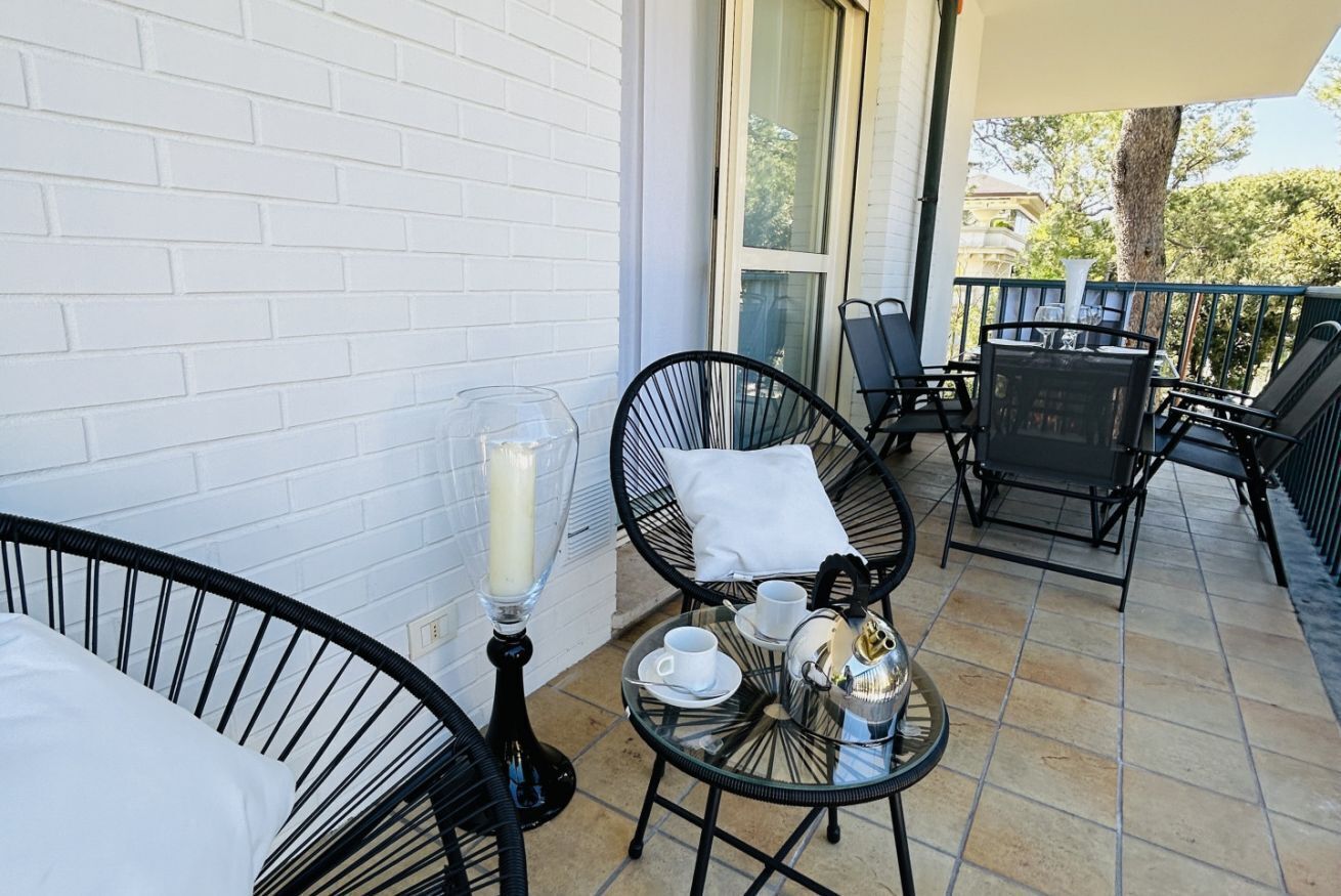 A balcony with wicker chairs, a glass table, and a candle.