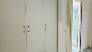 Un pasillo con un armario blanco y un vidrio que da a la zona de la ducha.