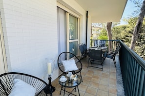 Un balcon avec une table et des chaises, une table en verre et une bougie.