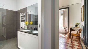 Un baño moderno con un espejo grande, dos lavamanos y una zona de ducha.