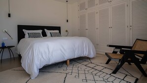 Et soveværelse med en stor seng, et sengebord, en stol og en garderobe med lægteporte.