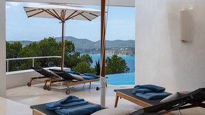 En balkon med liggestole, parasol og hav- og landskabudsigt.