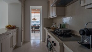 Et moderne køkken med udsigt, et spiseområde med bord og stole, samt en balkon med en hængende lampe.