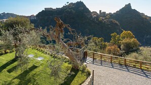 Vista panorámica de una zona montañosa con un camino que lleva a un edificio en la colina.