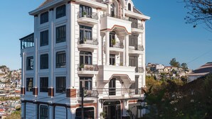 Un hôtel à plusieurs étages, doté de balcons, d’une entrée principale et offrant une vue sur le quartier environnant.