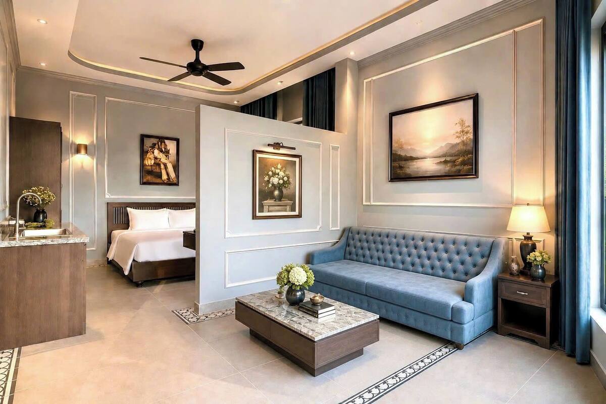A modern hotel room with a bed, a sofa, a coffee table, and a painting on the wall.