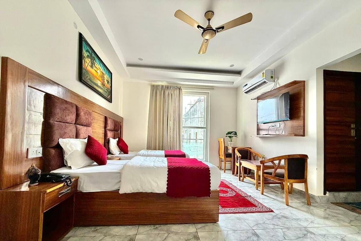 A hotel room with a large bed, a desk, a chair, a TV, and a ceiling fan.
