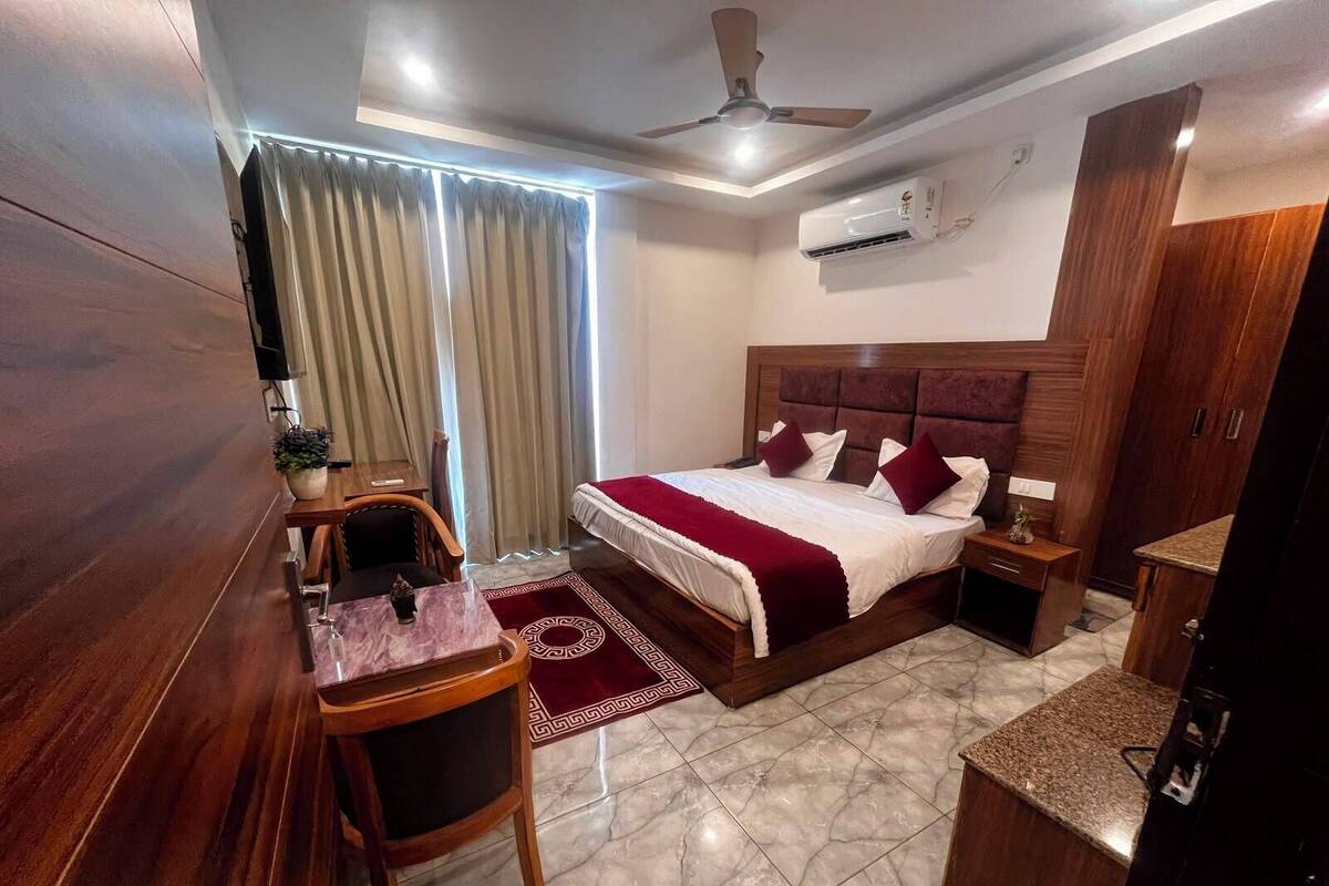 A hotel room with a bed, bedside table, nightstand, desk, chair, and a ceiling fan.