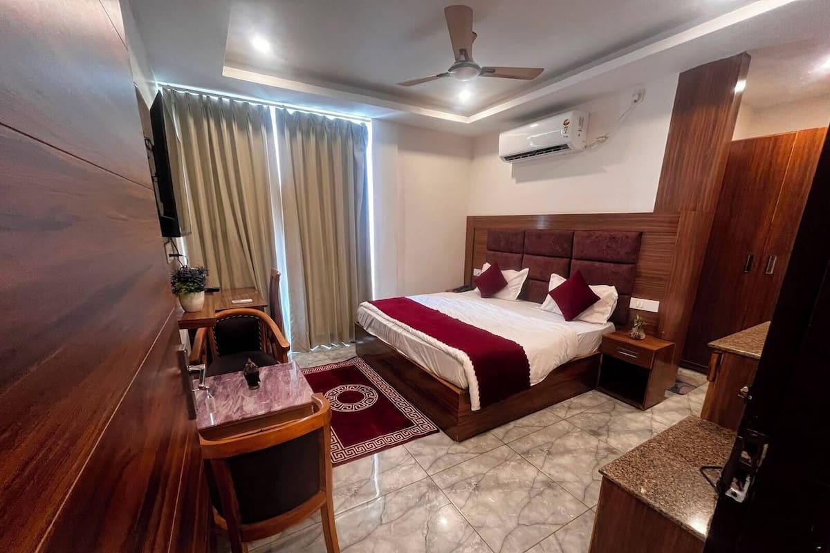 A hotel room with a bed, bedside table, nightstand, desk, chair, and a ceiling fan.