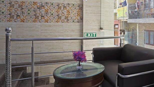 A lobby with a glass table, a sofa, a patterned wall, and an exit sign. - HOTEL STAR LITE (New Delhi)