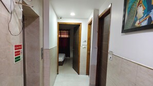 A hallway with a tiled floor, a painting on the wall, and a door at the end. - HOTEL STAR LITE (New Delhi)