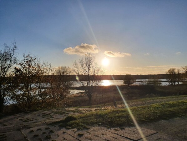A sunset over a body of water with trees in the foreground.