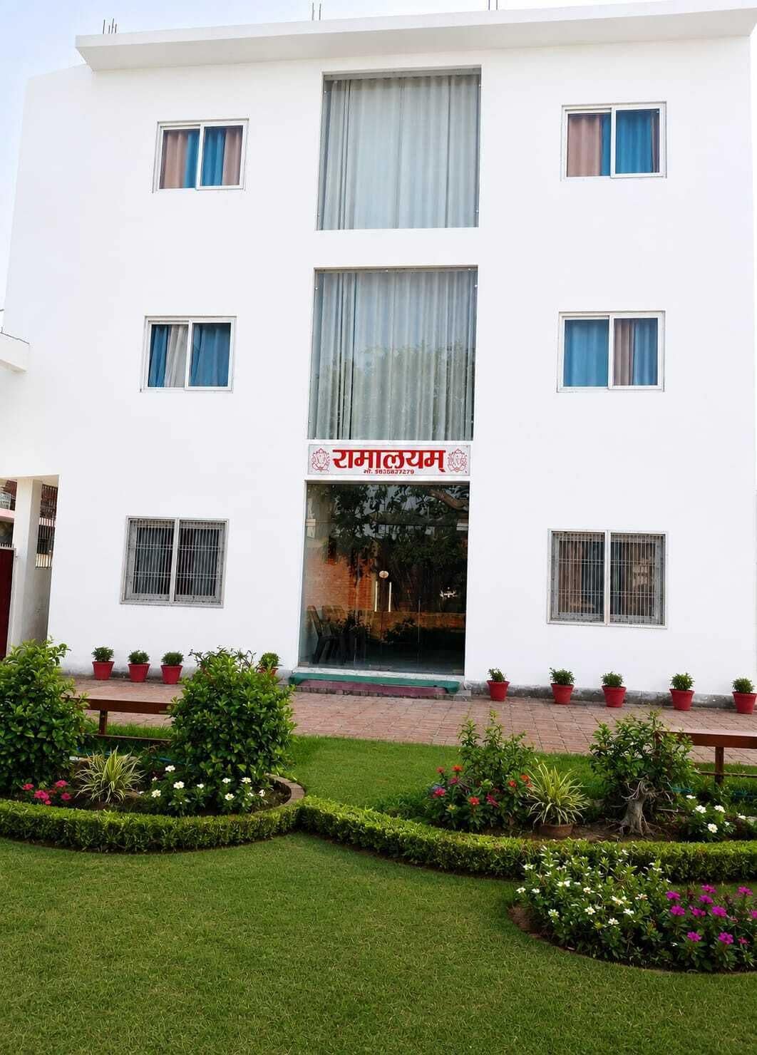 A white building with a sign reading 'RAMALYAM' and multiple windows.