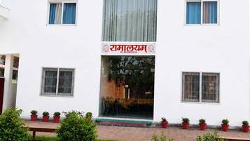 A white building with a sign reading 'RAMALYAM' and multiple windows.