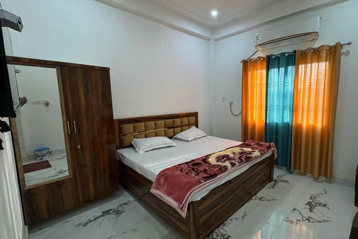 A bedroom with a bed, a wardrobe, an air conditioner, and a desk with a chair.