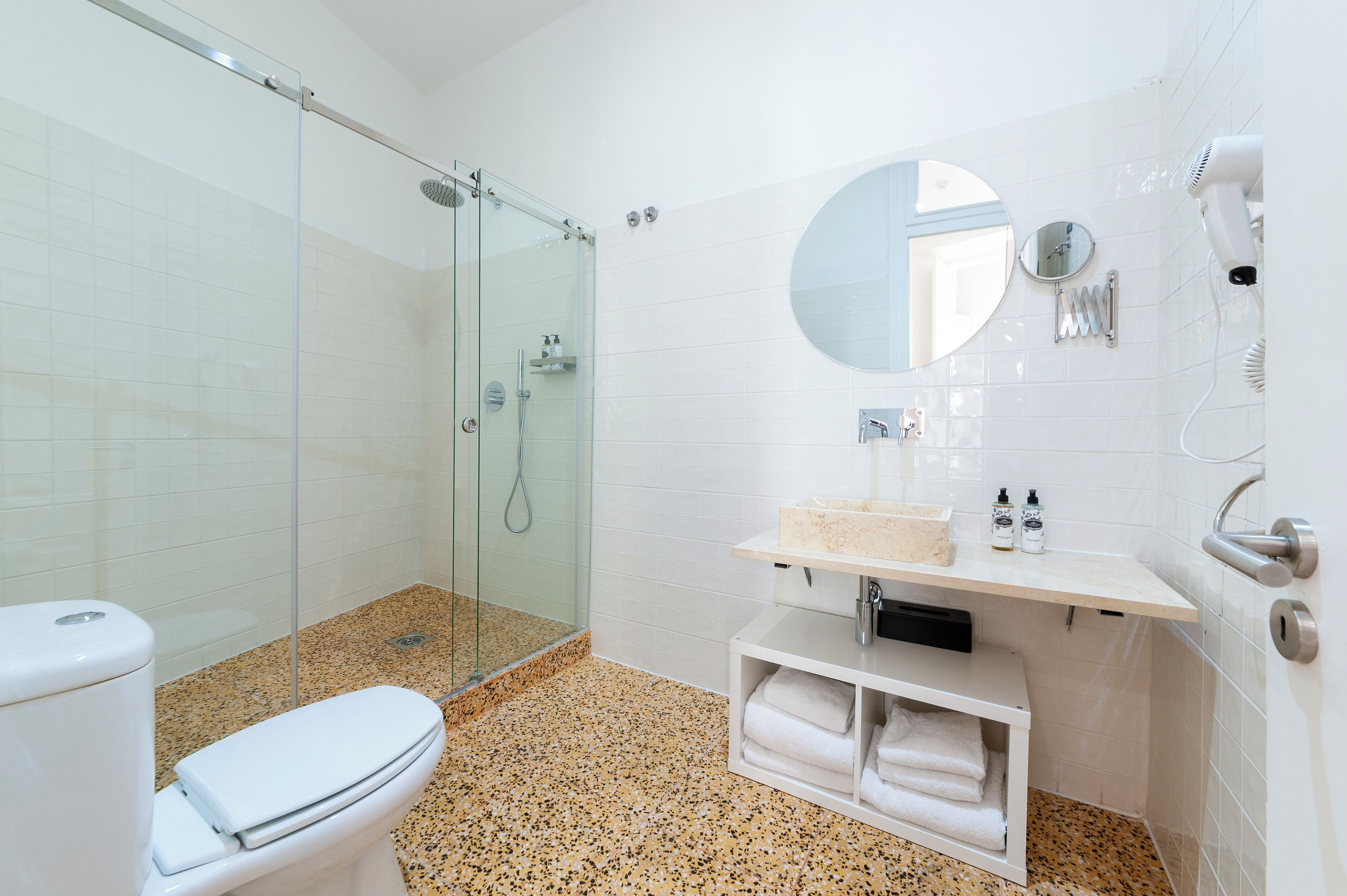 Une salle de bain avec une douche à parois de verre, des toilettes, un lavabo avec un miroir et un porte-serviettes.