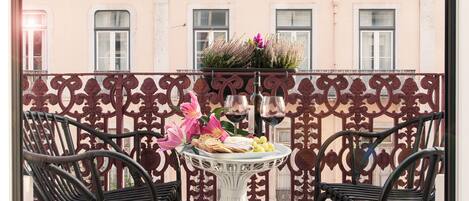 A balcony with a white table, two wicker chairs, and a decorative metal fence.