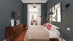 Un dormitorio con cama, cómoda, televisor y vistas al balcón.