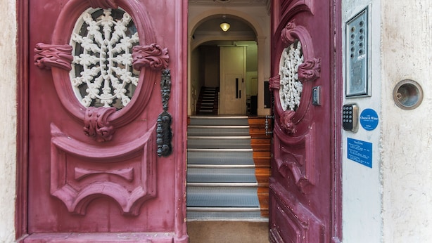 Una puerta roja con un tragaluz decorativo y una cerradura electrónica.