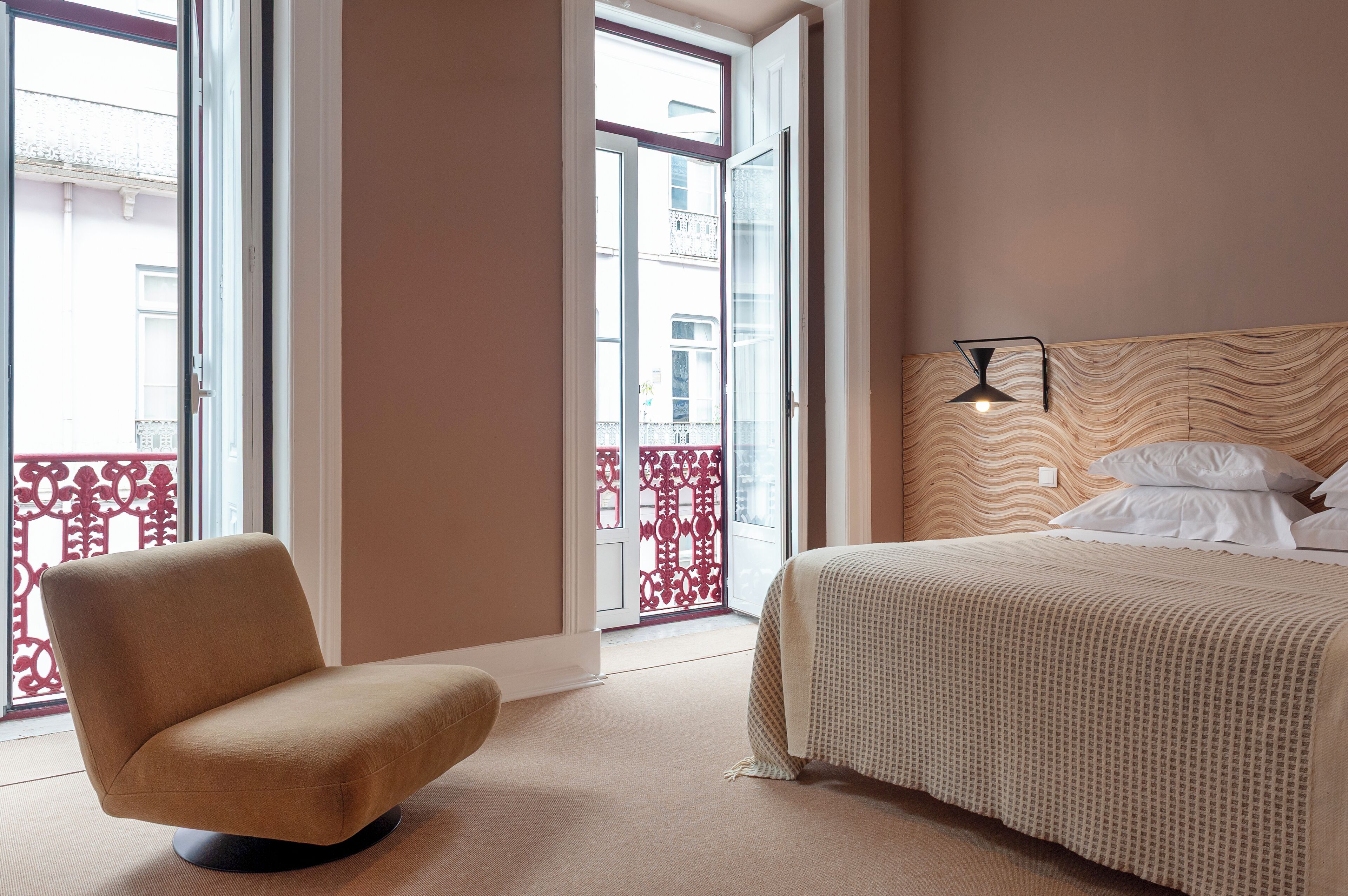 Een slaapkamer met een bed, een stoel en uitzicht naar buiten door een deur.