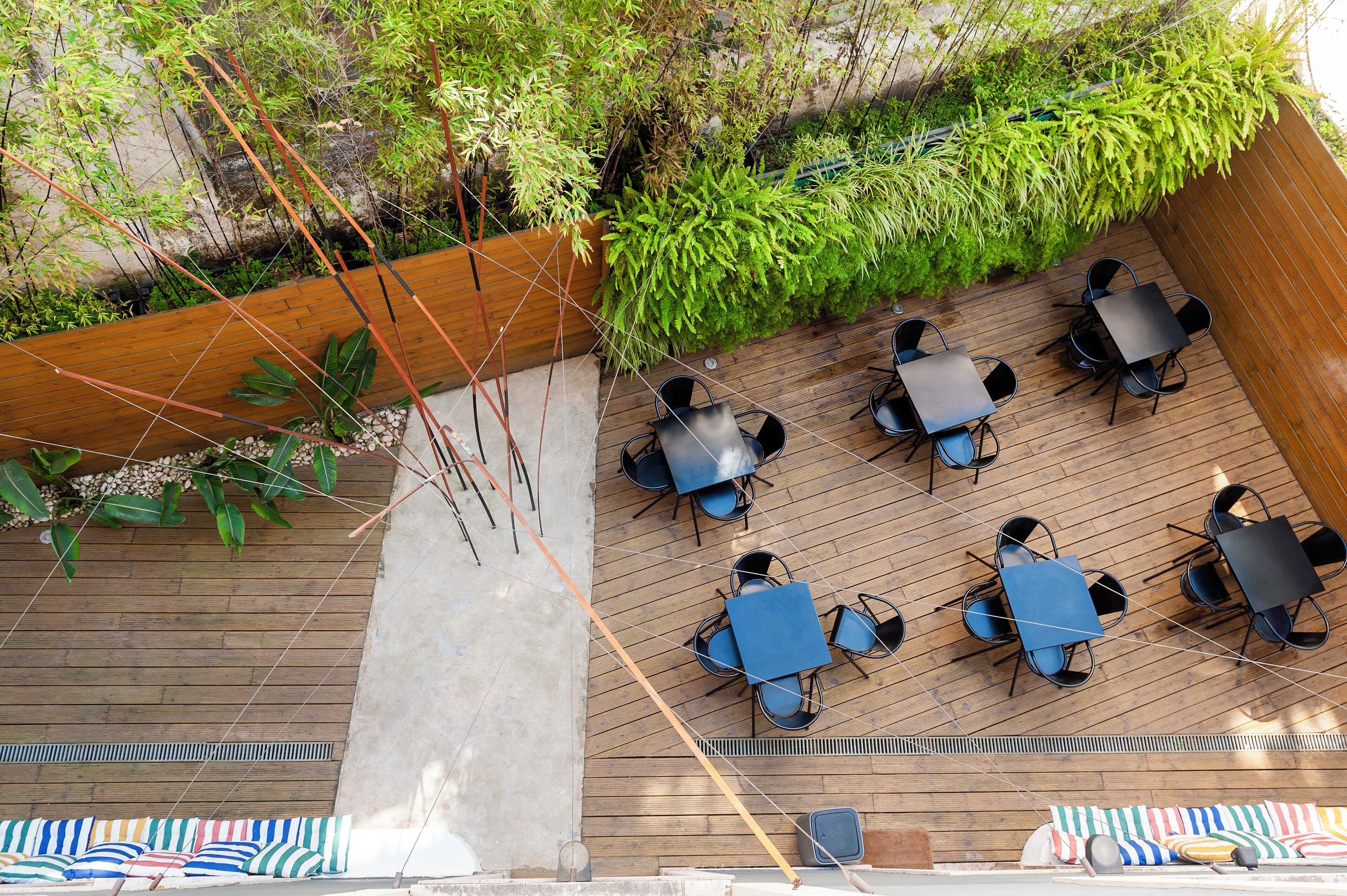An outdoor patio with wooden flooring, surrounded by greenery and bamboo plants.