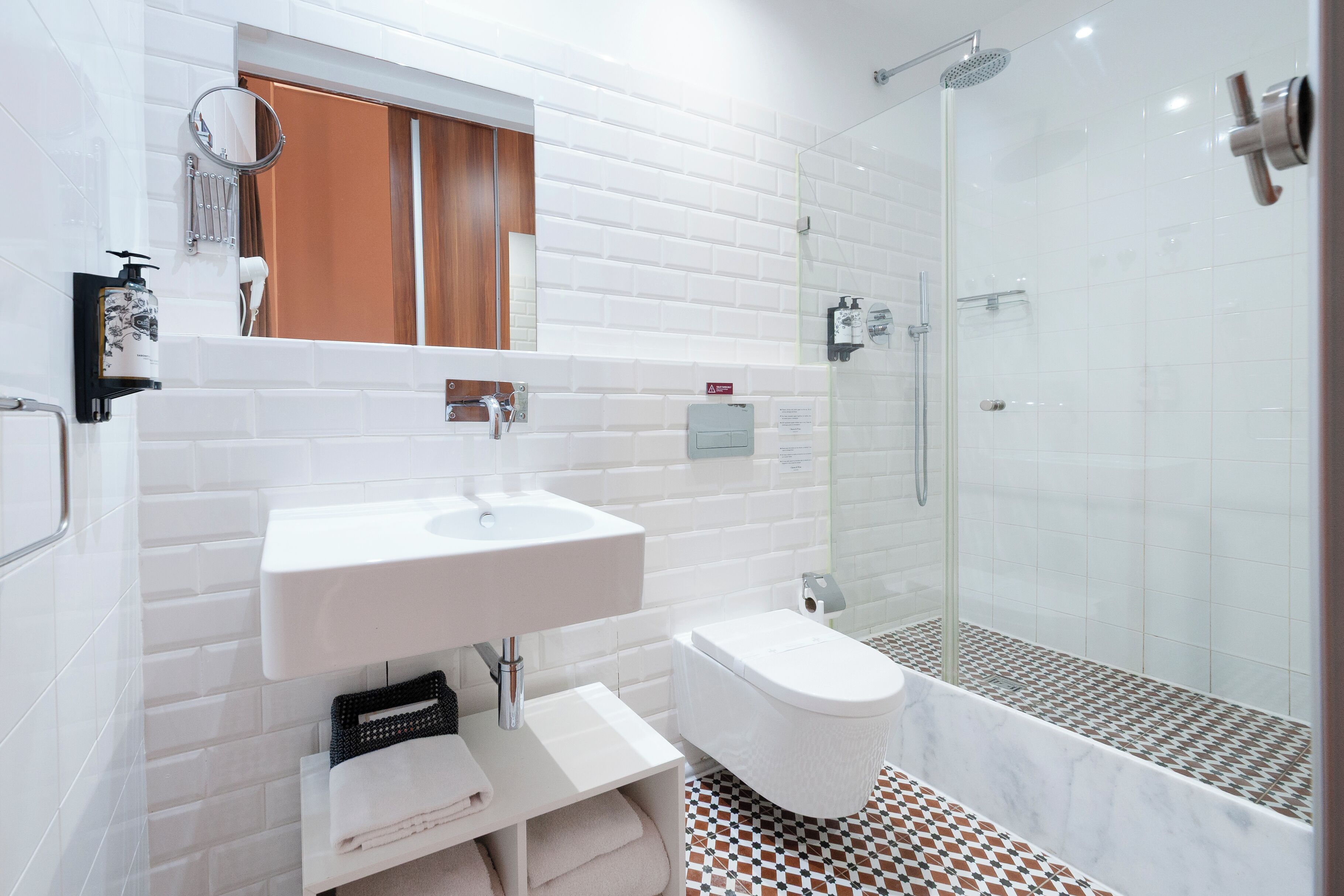 Un baño moderno con lavamanos, inodoro y ducha blancos.