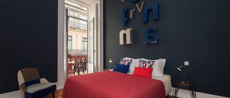 A bedroom with a bed, a chair, a nightstand, and a wall with letters spelling out a name.