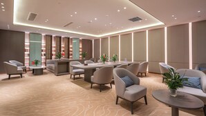 Un moderno vestíbulo de hotel con un área de estar central, estanterías y un mostrador de recepción.
