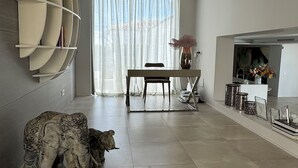 Un salon moderne comprenant un coin repas, une sculpture d’éléphant décorative et une grande fenêtre ornée de rideaux légers.