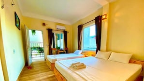 A hotel room with two beds, wooden flooring, a balcony, and a window with curtains. - Ha Lan Homestay (Ninh Binh)