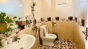 A bathroom with a shower, toilet, sink, and a patterned floor. - Ha Lan Homestay (Ninh Binh)