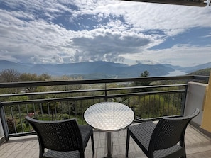 A balcony with a round table and two chairs, overlooking a mountainous landscape and a lake. - Al Ponte Hotel (Cademario)