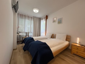 Ein Schlafzimmer mit zwei Betten, einem Schreibtisch und einem Stuhl.