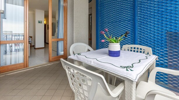 A balcony with a table, chairs, and a vase of flowers. - GuestHost - Comfortable Apartment with Sea View (Lido delle Nazioni)