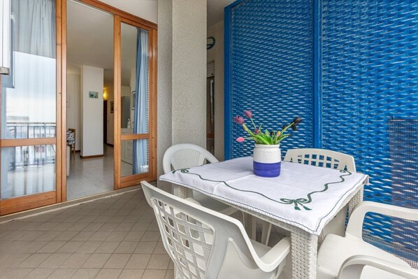 Un balcon avec une table, des chaises et un vase de fleurs.