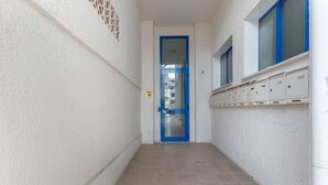 A narrow hallway with a blue door, a window with blue frames, and a row of storage boxes on the wall. - GuestHost - Comfortable Apartment with Sea View (Lido delle Nazioni)