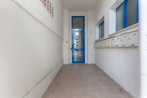 A narrow hallway with a blue door, a window with blue frames, and a row of storage boxes on the wall. - GuestHost - Comfortable Apartment with Sea View (Lido delle Nazioni)