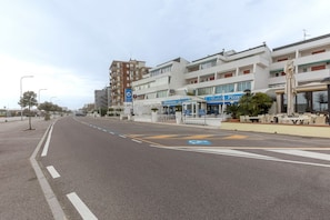 Une rue avec un passage piéton, des immeubles abritant des commerces et un ciel dégagé.