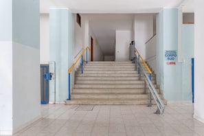 Un escalier doté d’une rampe métallique, d’une balustrade bleue et jaune, et d’une plaque indiquant « RÉSIDENCE ORSA MAGGIORE, BÂTIMENT SUD ».