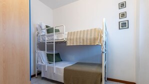 A bunk bed room with a wooden door, white walls, and three framed pictures on the wall. - GuestHost - Comfortable Apartment with Sea View (Lido delle Nazioni)