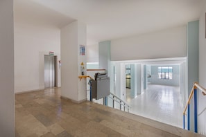 A spacious interior with a staircase, a visible elevator, and a clear view of another room through an open door.
