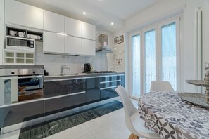 Une cuisine moderne dotée d’un îlot central, de meubles blancs et d’un coin repas agrémenté d’une nappe à motifs.
