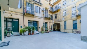 Une cour avec des plantes en pot, un vélo et un immeuble doté de plusieurs balcons.
